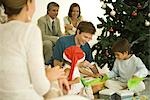 Père et ses deux enfants assis près de l'arbre de Noël, ouverture présente ensemble, famille regarder