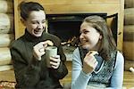 Teen girls having snack by fire place, laughing