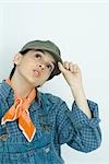 Teenage girl adjusting cap, looking up, portrait