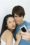 Jeune couple faisant face à l'appareil photo numérique ensemble