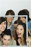 Young friends holding up frame together, smiling at camera