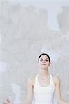 Woman sitting in lotus position, eyes closed, waist up