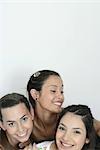 Three young female friends smiling, head and shoulders, portrait