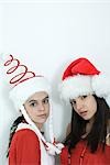 Two young female friends dressed in Christmas costumes, glaring at camera, portrait