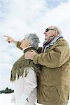 Senior couple standing together, looking up, man pointing