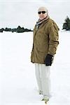 Senior man standing in snow, looking at camera, portrait