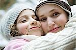 Two sisters embracing, smiling, one closing eyes, the other looking at camera, portrait