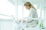 Woman sitting on porch, using laptop computer, smiling