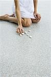 Woman kneeling on the ground arranging pebbles, cropped view