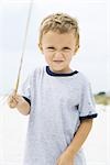 Young boy holding up stick, squinting at camera