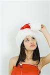 Teenage girl wearing Santa hat, looking up at pom-pom