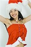 Teenage girl in Santa hat jumping with arms raised, smiling at camera