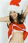 Teenage girl in Santa hat jumping, smiling at camera, midriff exposed