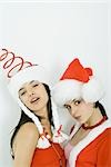 Two young friends wearing Santa hats, both looking at camera