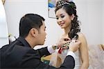 Groom pinning corsage on bride's dress