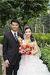 Bride and groom standing in verdant setting, portrait