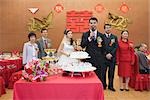 Groom standing in front of bride and parents, speaking into microphone