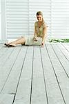 Woman sitting on deck playing solitaire, full length