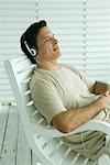 Man sitting in rocking chair, listening to headphones