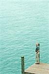 Homme debout à côté d'eau écouter écouteurs, levant, vue grand angle