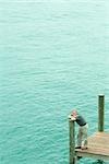 Homme debout sur le quai, se penchant sur le post, vue grand angle