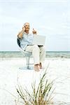 Senior man using laptop and cell phone on beach