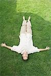 Man lying on back in grass, smiling at camera, high angle view