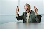 Businessman making peace signs with both hands, smiling at camera