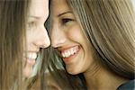 Two twin teenage sisters smiling, face to face, profile