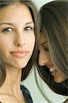 Two twin teenage sisters smiling, one looking at camera