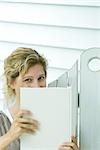 Woman looking over book at camera, close-up