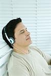 Man listening to headphones, eyes closed, side view