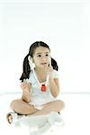 Little girl sitting next to teddy bear, listening to toy stethoscope