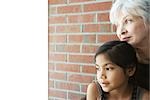 Senior Woman Ruhe von ihrem Kinn auf Enkelin Kopf, beide Wegsehen, Nahaufnahme