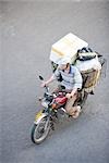 Man riding moped loaded with boxes, high angle view