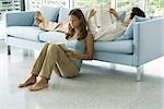 Jeune couple, lire des livres ensemble, hommes couché sur le canapé, femme assise sur le plancher