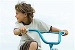 Boy riding bicycle, looking over shoulder, close-up