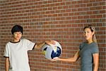 Woman and boy holding globe wrapped in bandages, both looking at camera