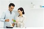 Couple cooking together, woman holding fresh basil