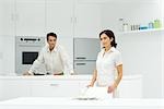 Couple in kitchen, man preparing meal, woman setting table
