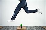 Man jumping in the air over bonsai, side view, cropped