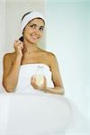 Young woman in towel applying perfume, smiling