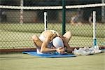 Teenage girl sitting on mat on the ground, bending over, stretching