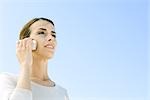 Woman using cell phone outdoors, looking away, low angle view