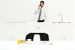 Businessman standing in kitchen, using cell phone, focus on breakfast in foreground