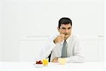 Homme assis à table, manger petit déjeuner sain, regardant la caméra