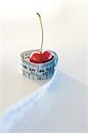 Measuring tape wrapped around cherry, close-up
