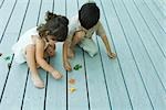 Two young friends crouching together, playing with toys, high angle view