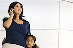 Mother and daughter standing side by side, listening to headphones