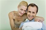 Couple holding new baby wrapped in blanket, smiling, man looking at camera